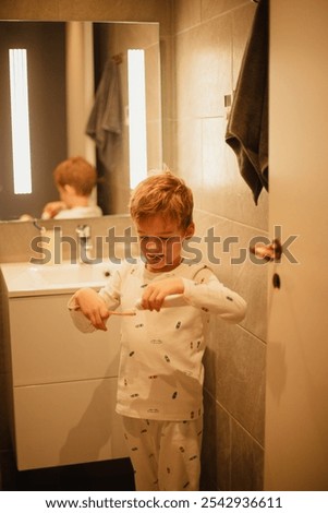 Young boy brushing his teeth independently in a bathroom, practicing good dental hygiene. Ideal for concepts of health, self-care, and children's daily routines.