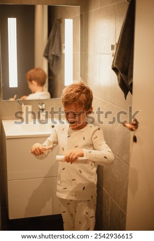 Young boy brushing his teeth independently in a bathroom, practicing good dental hygiene. Ideal for concepts of health, self-care, and children's daily routines.