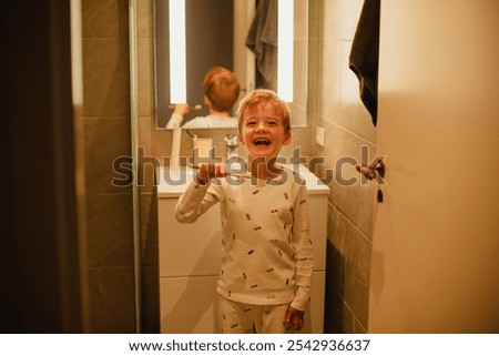 Young boy brushing his teeth independently in a bathroom, practicing good dental hygiene. Ideal for concepts of health, self-care, and children's daily routines.