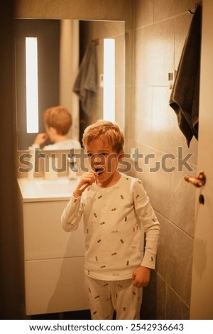 Young boy brushing his teeth independently in a bathroom, practicing good dental hygiene. Ideal for concepts of health, self-care, and children's daily routines.
