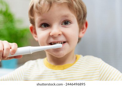 Young boy brushing teeth with electric toothbrush. - Powered by Shutterstock