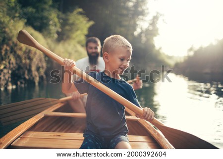 Young boy canoeing on the lake with his father