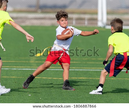Young boy catching, running and throwing the ball in a football game