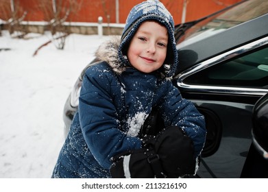 Young Boy Charging Electric Car In The Yard Of House At Winter.