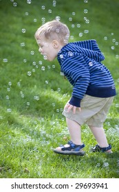 Young boy chasing and trying to catch bubbles