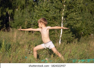 Young Boy Child Practices Yoga, Standing Of Yoga Warrior Pose, Exercising Virabhadrasana Pose Outdoor.