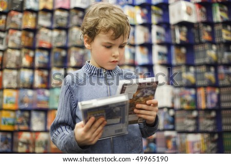 young boy chooses one of two dvd in special store, ready contents