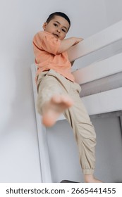 Young boy climbing down from a bunk bed at home. Scene reflects childhood behavior, independence, active movement, and everyday life in a real family environment. High quality photo