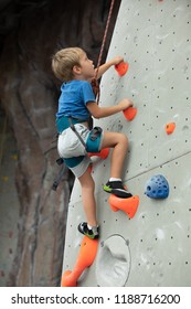 Young Boy Climbing Up An Indoor Wall At The Rock Climbing Gym