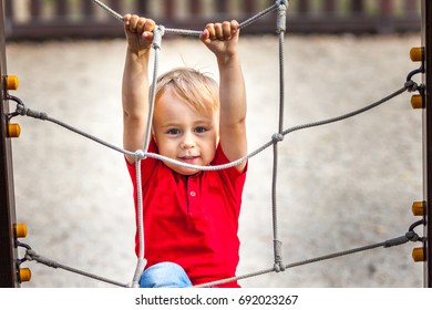 Young Boy Climbing Rope Obstacle On Kid Playground