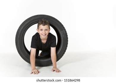 Young Boy Is Climbing Through A Tire