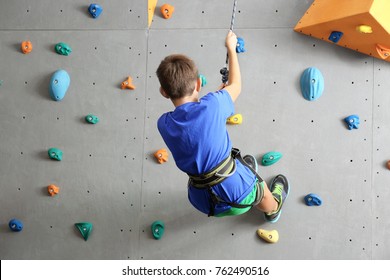 Young boy climbing wall in gym