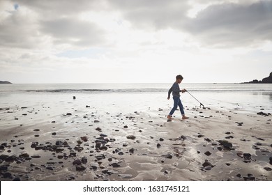 Young Boy Collecting Litter On Winter Beach Clean Up