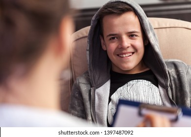 Young boy in counseling session at the psychologist or social services professional, laughing, not taking it seriously, close up