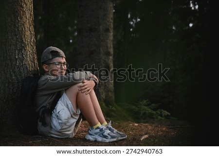 Young boy crying in a dark forest, feeling lost and alone while hugging his knees, surrounded by towering trees and shadows of despair