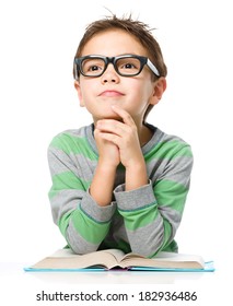 Der junge Junge träumt beim Lesen des Buches und trägt eine Brille einzeln auf Weiß