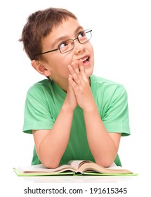 Young boy is daydreaming while reading book and wearing glasses, isolated over white