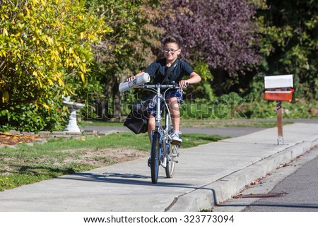 A young boy delivering newspapers on his bicycle