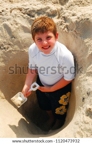 A young boy digs himself deeper into the sand on a summer's day