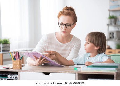 Young boy doing homework during extra-curricular classes with a tutor