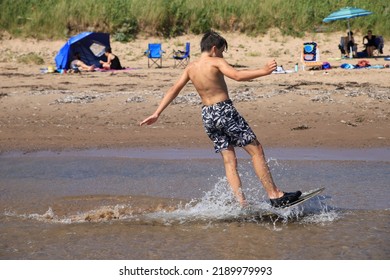 Young Boy Doing Skimboard On The Beach