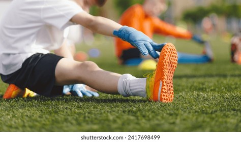 Young Boy Doing Soccer Stretching Exercises. Kids in Football Goalkeepers Training. Group of School Boys in Soccer Goalie Practice During Summer Time. Youth players in Soccer Gloves and Cleats - Powered by Shutterstock