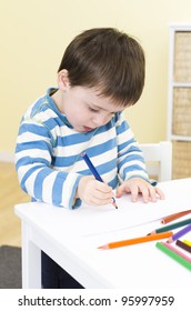 Young boy draws with a blue pencil