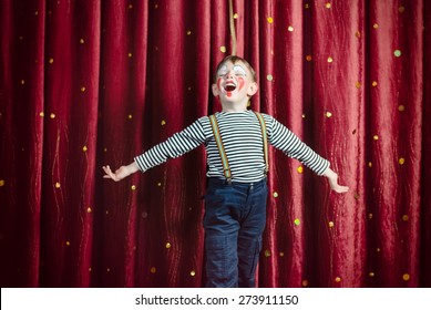 Young Boy Dressed as Clown Performing on Stage with Open Arms and Open Mouth as if Singing or Acting - Powered by Shutterstock