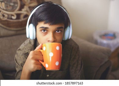 Young boy drinking coffee at home with listening to music