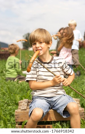 Young boy eating hot dog at campfire