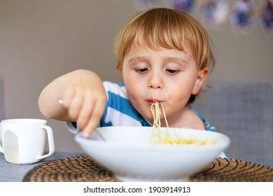 Young Boy  Eating Italian Pasta At Home. Little Child Enjoying Spaghetti Meal Indoors. Cute Kid And Healthy Food