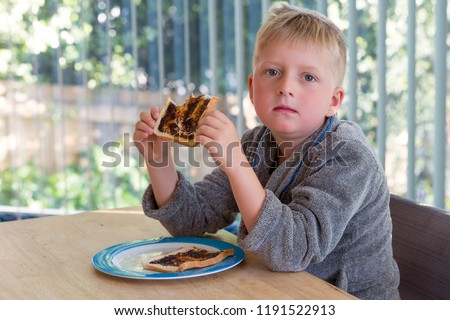 Young boy eating vegemite toast for breakfast 