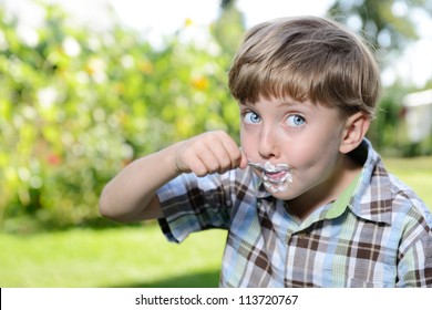 A Young Boy Eating A Yogurt