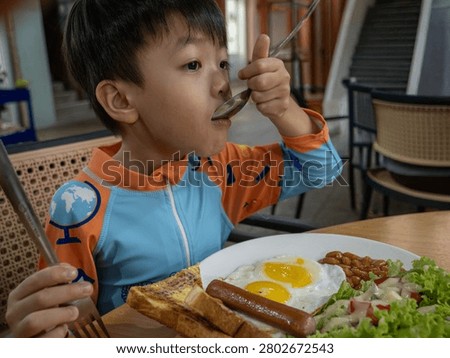 A young boy eats a full breakfast meal at a restaurant.