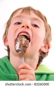 Young Boy Enjoying Licking Chocolate Cake Mixture Off A Spoon