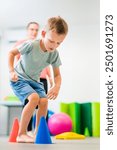 Young boy exercising with female physical therapist during therapy session. Child occupational physical therapy. Bilateral coordination.