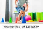 Young boy exercising with female physical therapist during therapy session. Child occupational physical therapy. Bilateral coordination.