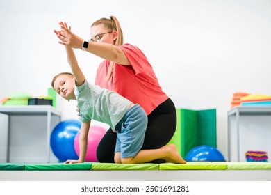 Young boy exercising with female physical therapist during therapy session. Child occupational physical therapy. Bilateral coordination. - Powered by Shutterstock