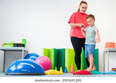 Young boy exercising with female physical therapist during therapy session. Child occupational physical therapy. Bilateral coordination. - Powered by Shutterstock