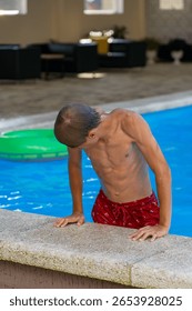 A young boy exiting a refreshing blue swimming pool on a warm summer day, illustrating active recreational fun and relaxation.