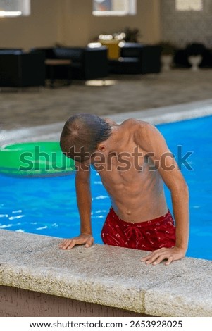 A young boy exiting a refreshing blue swimming pool on a warm summer day, illustrating active recreational fun and relaxation.