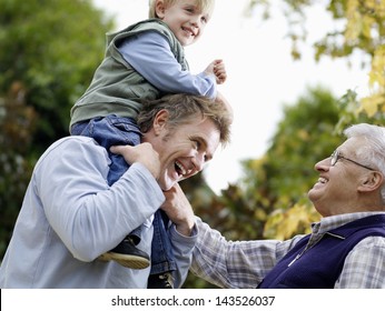 Young Boy With Father And Grandfather Enjoying Together In Park