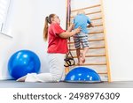 Young boy with female physical therapist exercising during therapy session. Child occupational physical therapy. Bilateral coordination.