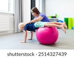 Young boy with female physical therapist exercising using ball during therapy session. Child physical therapy. Bilateral coordination.