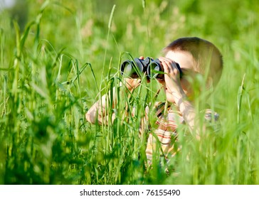 Young boy in a field looking through binoculars - Powered by Shutterstock