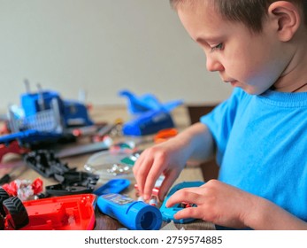 Young boy focused on disassembling colorful toy construction set on cluttered table, chaotic creative play and learning moment