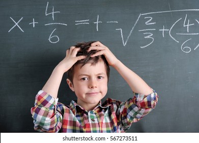 Young boy in front of blackboard with mathematical problem grabbing his hair