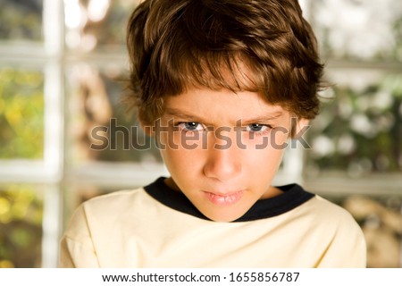 Young boy frowning, well lit
