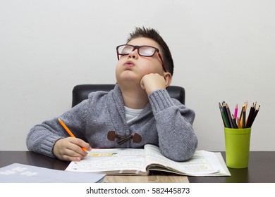 Young Boy Frustrated Over Homework, Writing At Home. Boy Studying At Table. Kid Drawing With A Pencil