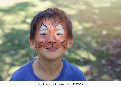 Young Boy With Fun Face Painting As A Tiger